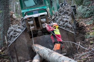 Florian Mathieu, bûcheron, tire le câble du tracteur débardeur pour accrocher un tronc. Chantier à Châtel en Trièves, Isère